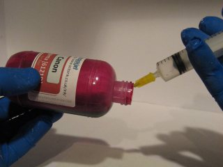 Careful tipping and a one handed approach on the syringe to getting the last ink out of your bottle
